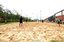 Teams of Headquarters and Headquarters Squadron await a volleyball during a game at the Commander's Cup volleyball game, April 19. 