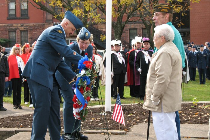 Rome community members stand while Lt. Col. Wendy Rickards, Northeast Air Defense Sector Canadian Component commander, and Warrant Officer Norm Macoomb, NEADS Canadian Component unit warrant officer, place a wreath next to the Northeast Air Defense Sector's wreath during a joint, bi-national Veterans Day ceremony in Rome, N.Y.