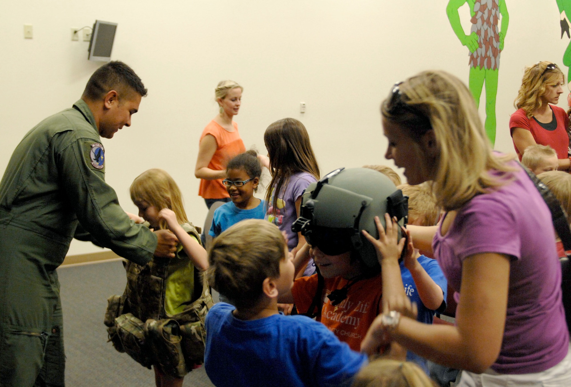 U.S. Air Force Airman 1st Class Ricardo Tinoco, 55th Rescue Squadron aerial gunner, helps a child from the Family Life Academy try on personal protective gear during their visit to the 55th RQS at Davis-Monthan Air Force Base, Ariz., April 24, 2013. More than 20 students, along with family members, visited the 358th Fighter Squadron and the 55th RQS to get an inside look at their mission. (U.S. Air Force photo by Airman 1st Class Saphfire Cook/Released)