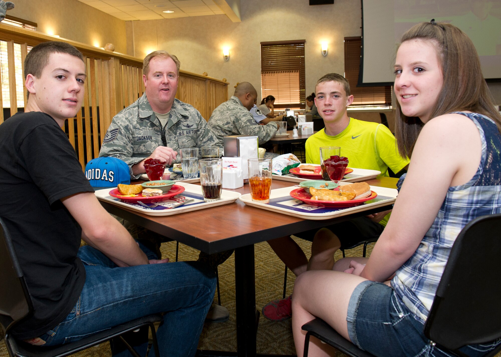 Tech. Sgt. Jeremy Jackson, 4th Space Control Squadron crew chief, has lunch with his children, Jason, Kori and Cody, at the Shifting Sands Dining Facility Take Your Kid to Work Day at Holloman Air Force Base, N.M., April 22. The event was held in April for the Month of the Military Child. (U.S. Air Force photo by Senior Airman Kasey Close/Released)