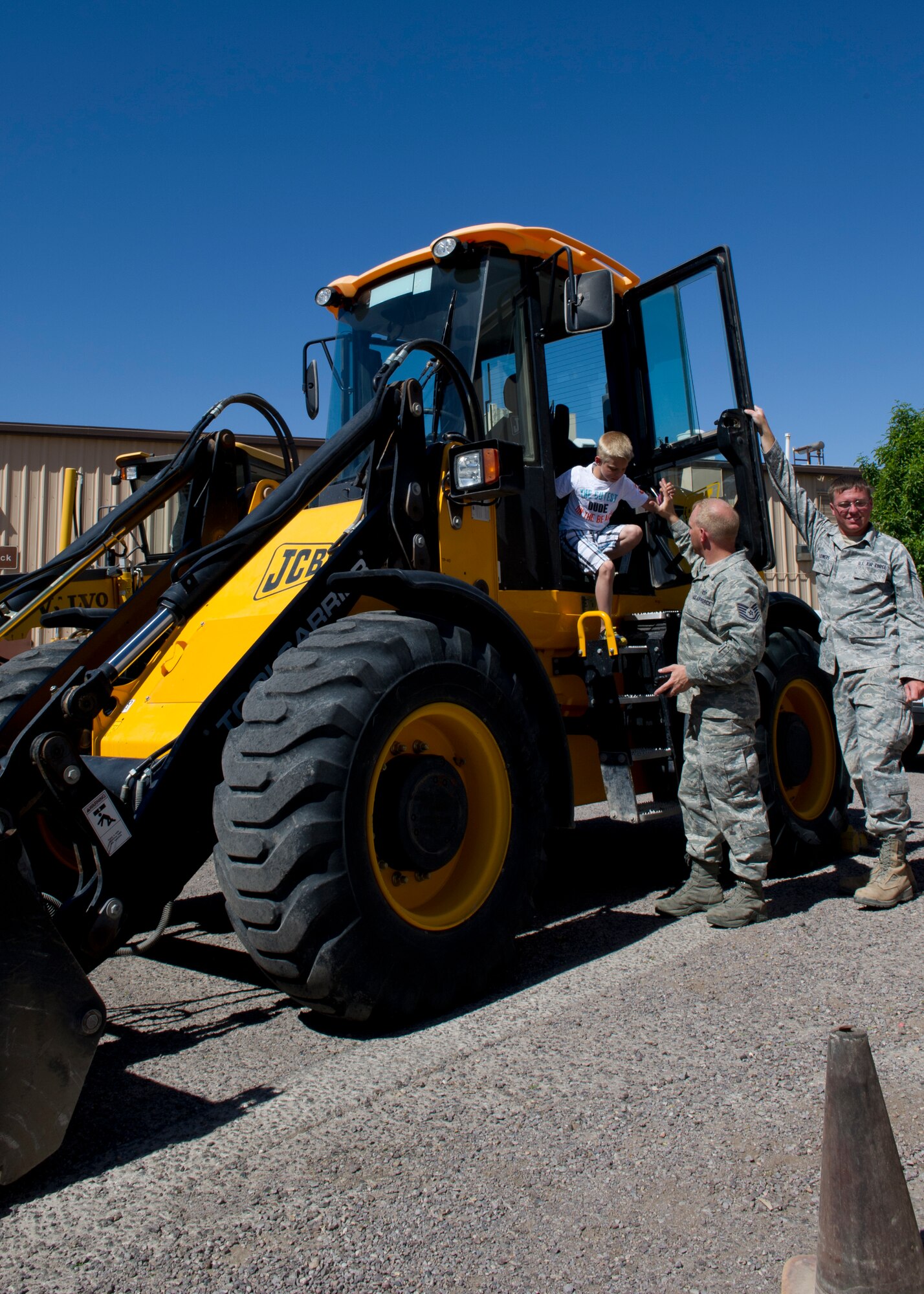 Tech. Sgt. Jason Brown, 49th Civil Engineer Squadron heating, ventilation, and air conditioning craftsman, helps his son, Blake, out of a front-loader during Take Your Kid to Work Day at Holloman Air Force Base, N.M., April 22. Children toured the different work areas of the CES and experienced various equipment in the squadron. (U.S. Air Force photo by Senior Airman Kasey Close/Released)