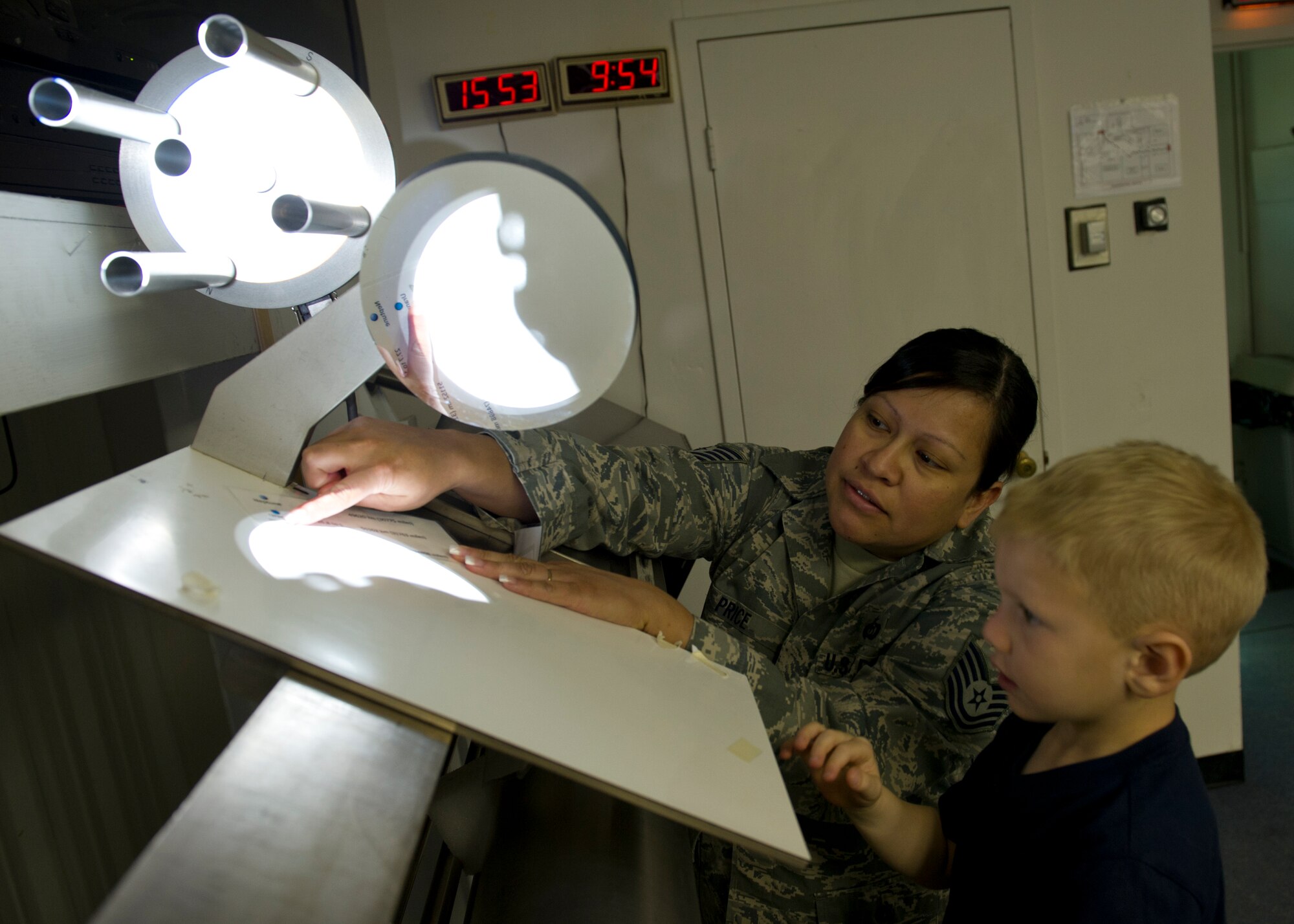 Tech. Sgt. Braulia Price, Detachment 4, 2nd Weather Squadron solar observatory NCO in charge, shows John Siebert how to measure sun spots by comparing them to the size of the planets during Take Your Kid to Work Day at Holloman Air Force Base, N.M., April 22. John went to work with his father, Senior Master Sgt. Shane Siebert, Det. 4, 2nd WS solar observatory chief. (U.S. Air Force photo by Senior Airman Kasey Close/Released)