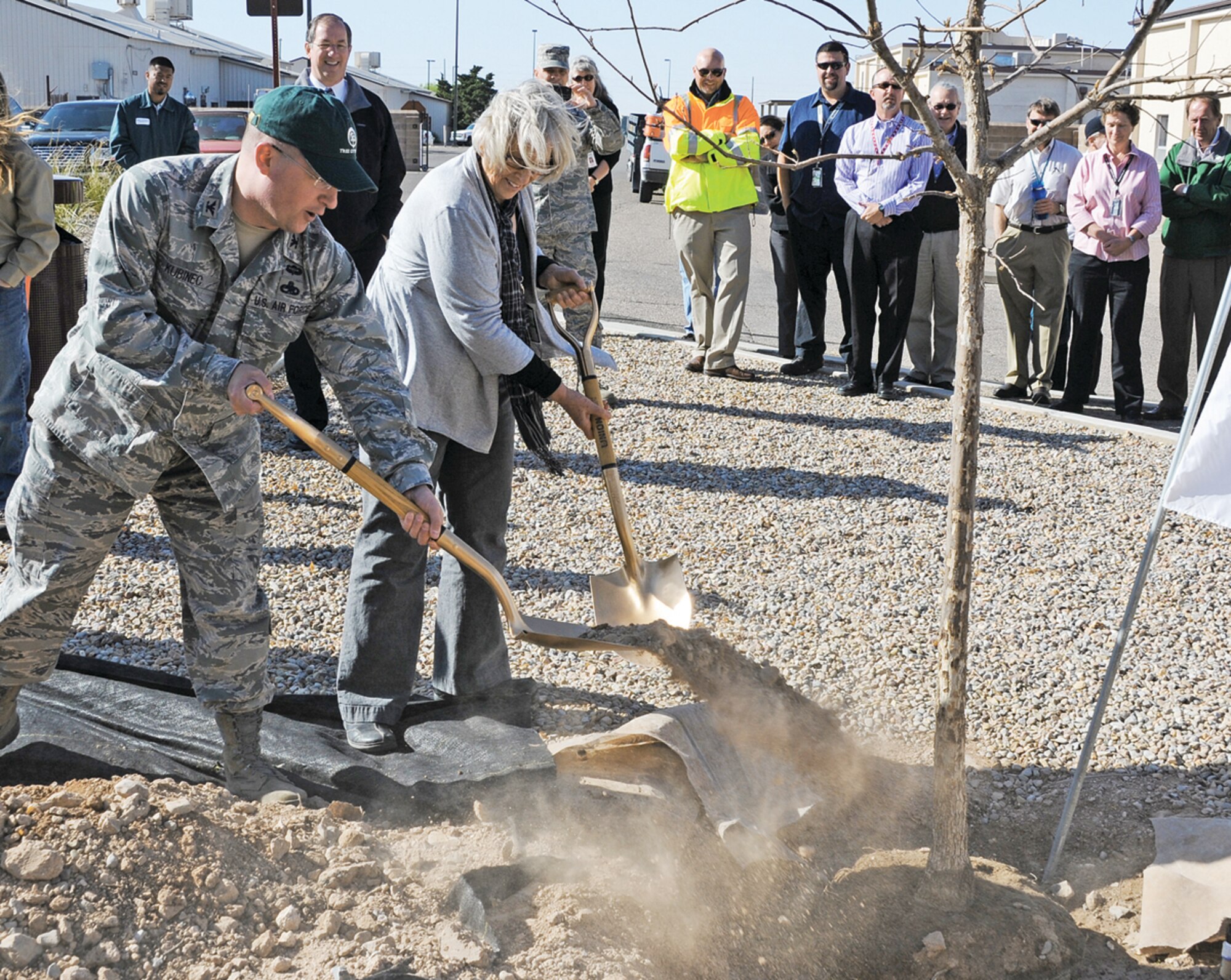 Col. John Kubinec, 377th Air Base Wing commander, left, dons a Tree City USA cap and joins Donna Dunn, base community planner, in planting a new tree in the southwest corner of the 377 ABW headquarters building. The tree, a Chinquapin Oak, was planted in recognition of the base achieving Tree City status. (Photo by Dennis Carlson)