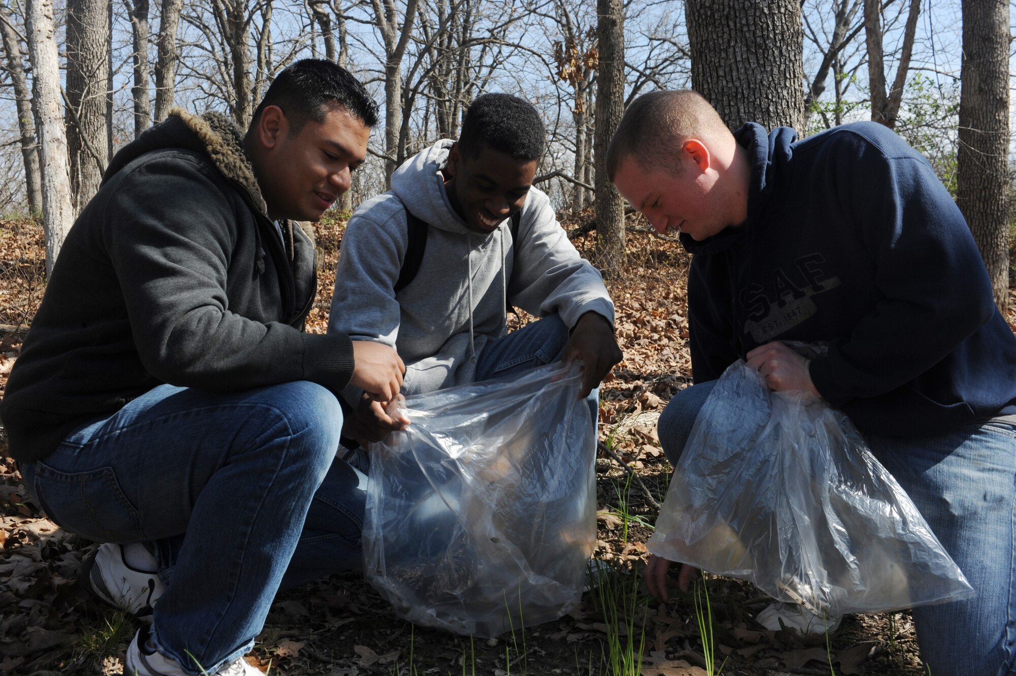 Airman 1st Class Manuel Gurrion (left), and Airman 1st Class Devyn Ransom and Senior Airman James Davis, 509th Maintenance Squadron aerospace ground equipment maintainers, pick up trash during a trash collection at Knob Noster State Park, Mo., April 20, 2013. Members of Team Whiteman were joined by spouses and dependents in carrying out the mass cleanup. (U.S. Air Force photo by Airman 1st Class Bryan Crane/Released)