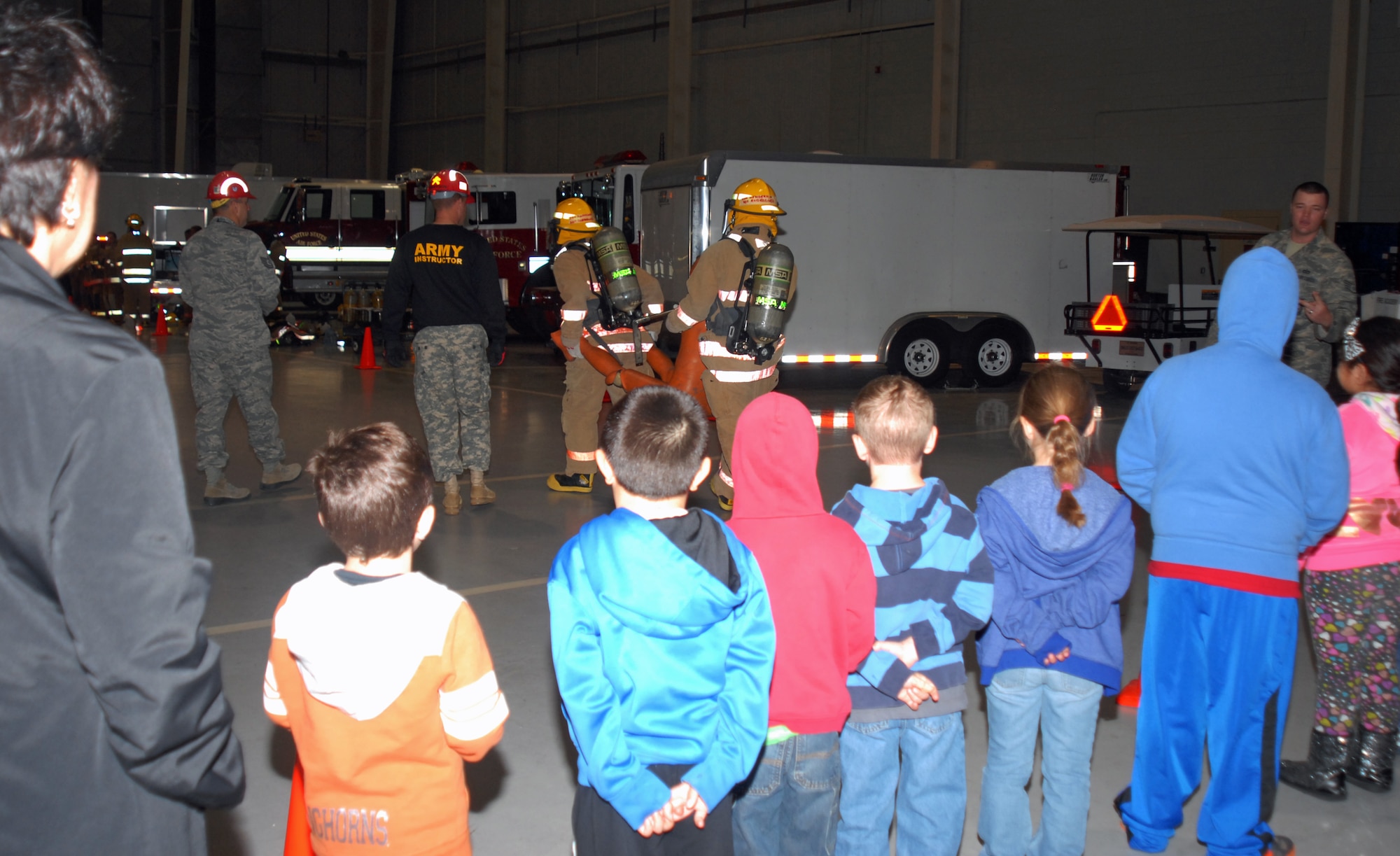 GOODFELLOW AIR FORCE BASE, Texas—Youths watch trainees carry a dummy in the Louis F. Garland Fire Academy high bay, here, April 23. The children visited Goodfellow from Santa Rita Elementary School in San Angelo. 