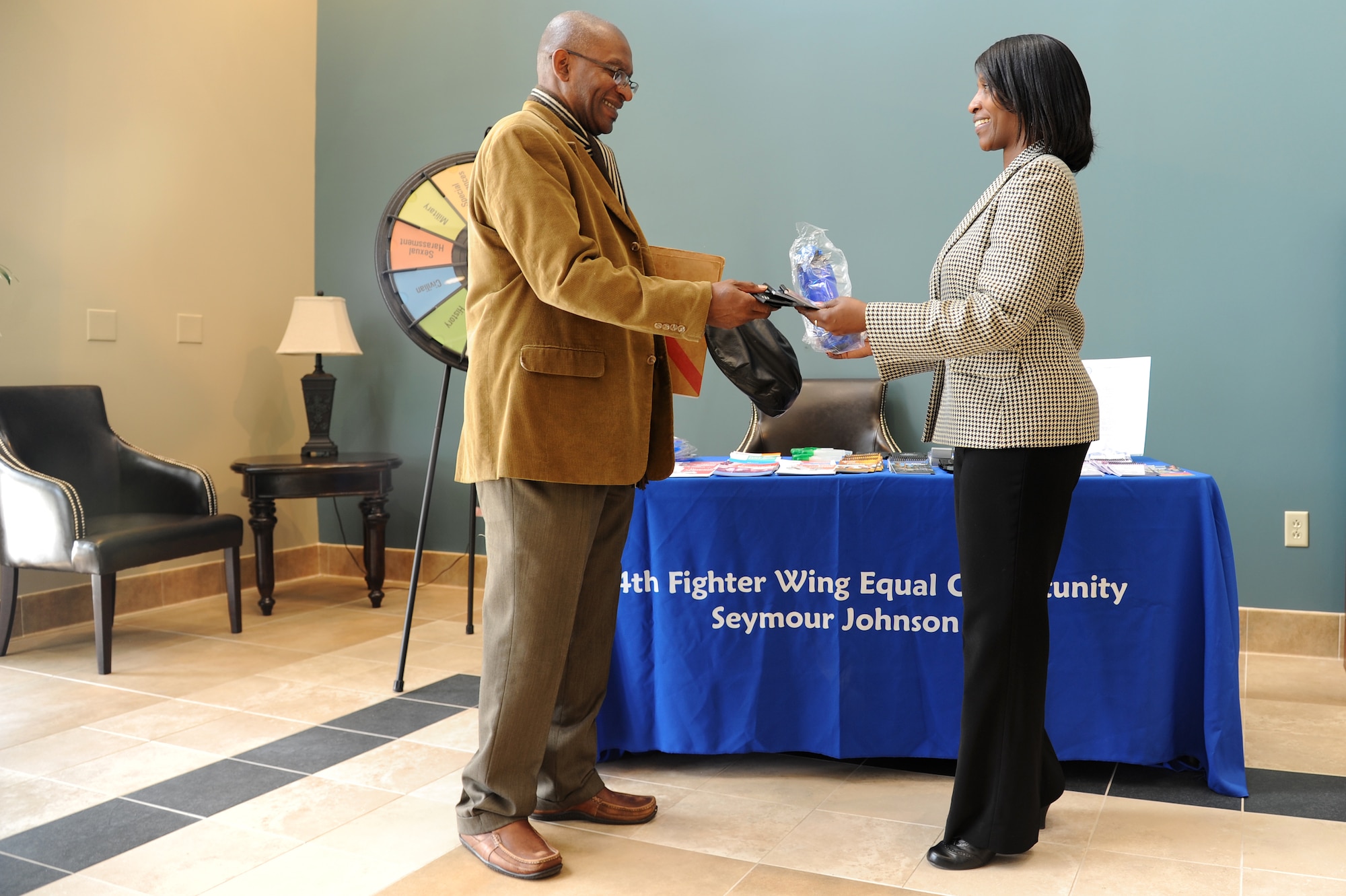 Rhonda Christie, 4th Fighter Wing Equal Opportunity director, presents Robert Pinder, 4th Force Support Squadron customer service representative, with some gifts at an EO information fair on Seymour Johnson Air Force Base, N.C., April 23, 2013.  The event helped spread awareness of services the EO office provides visitors and base personnel.  (U.S. Air Force photo by Airman 1st Class Brittain Crolley/Released)