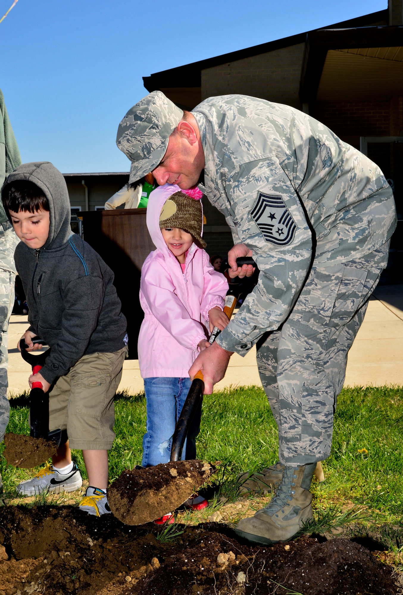 Chief Master Sgt. Jim Smith, 436th Airlift Wing command chief, helps a little girl plant a tree in front of the Child Development Center April 25, 2013, at Dover Air Force Base, Del. Smith and the children were planting trees in celebration of Earth Day. (U.S. Air Force photo/David Tucker)