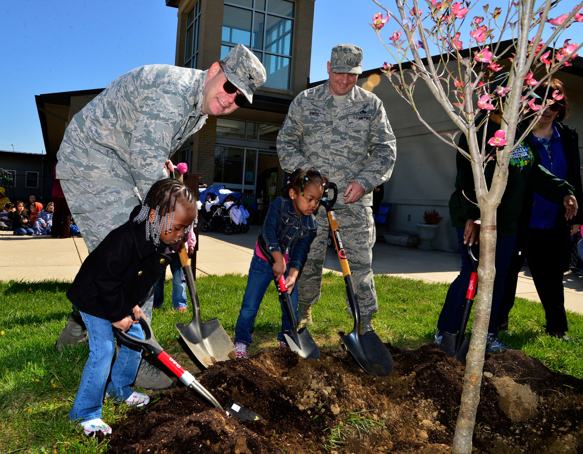 Col. Rick Moore, 436th Airlift Wing commander, and Chief Master Sgt. Jim Smith, 436th AW command chief, help children plant a tree in front of the Child Development Center April 25, 2013, at Dover Air Force Base, Del. Col. Moore, Chief Smith and the children were planting a tree in commemoration of Earth Day. (U.S. Air Force photo/David Tucker)