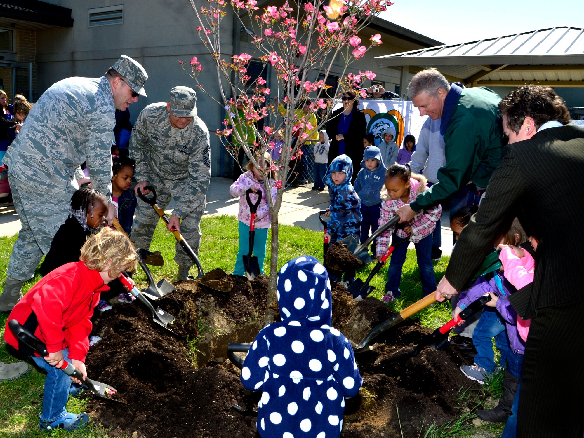 Col. Rick Moore, 436th Airlift Wing commander, and Chief Master Sgt. Jim Smith, 436th AW command chief, plant a tree with children April 25, 2013, at the Child Development Center on Dover Air Force Base, Del. Col. Moore and the children were planting a tree in celebration of Earth Day. (U.S. Air Force photo/David Tucker)