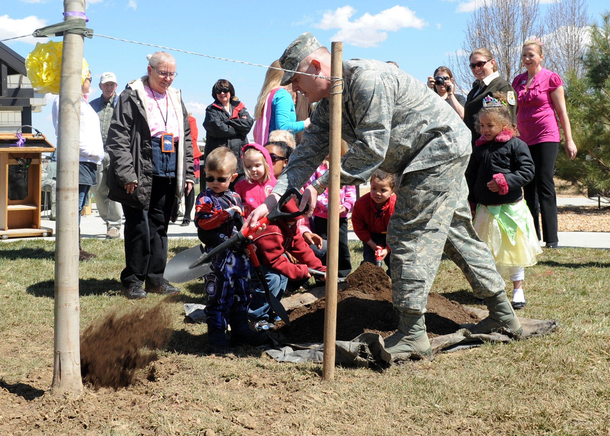 Col. Dan Dant, 460th Space Wing commander, shovels dirt April 24, 2013, at Buckley Air Force Base, Colo. Dant demonstrated to children at the A-Basin Child Development Center how to shovel dirt onto the newly planted blazing maple tree planted in honor of Arbor Day. (U.S. Air Force photo by Senior Airman Marcy Glass/Released)