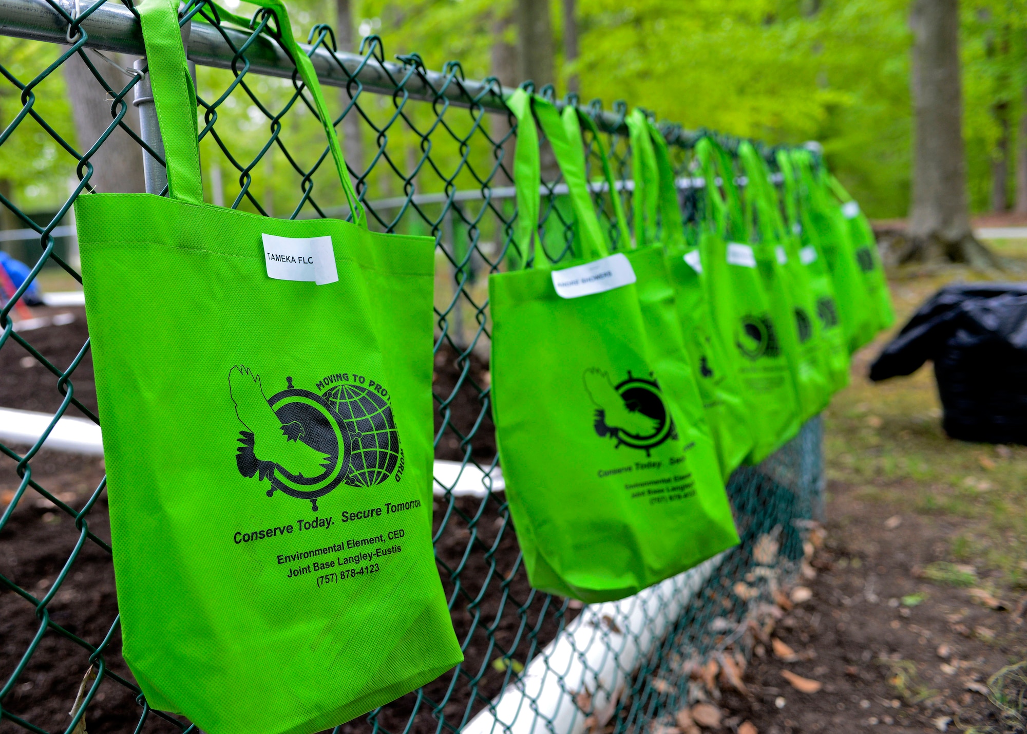 Reusable bags made of recycled material hang on the park fence at the Outdoor Recreation Campground as 93rd Signal Brigade Soldiers cleaned the area in support of Earth Week at Fort Eustis, Va., April 23, 2013. More than 230 volunteers joined environmental protection officials at Langley Air Force Base and Fort Eustis in a series of clean-up and educational projects on each installation. (U.S. Air Force photo by Airman 1st Class R. Alex Durbin/Released)