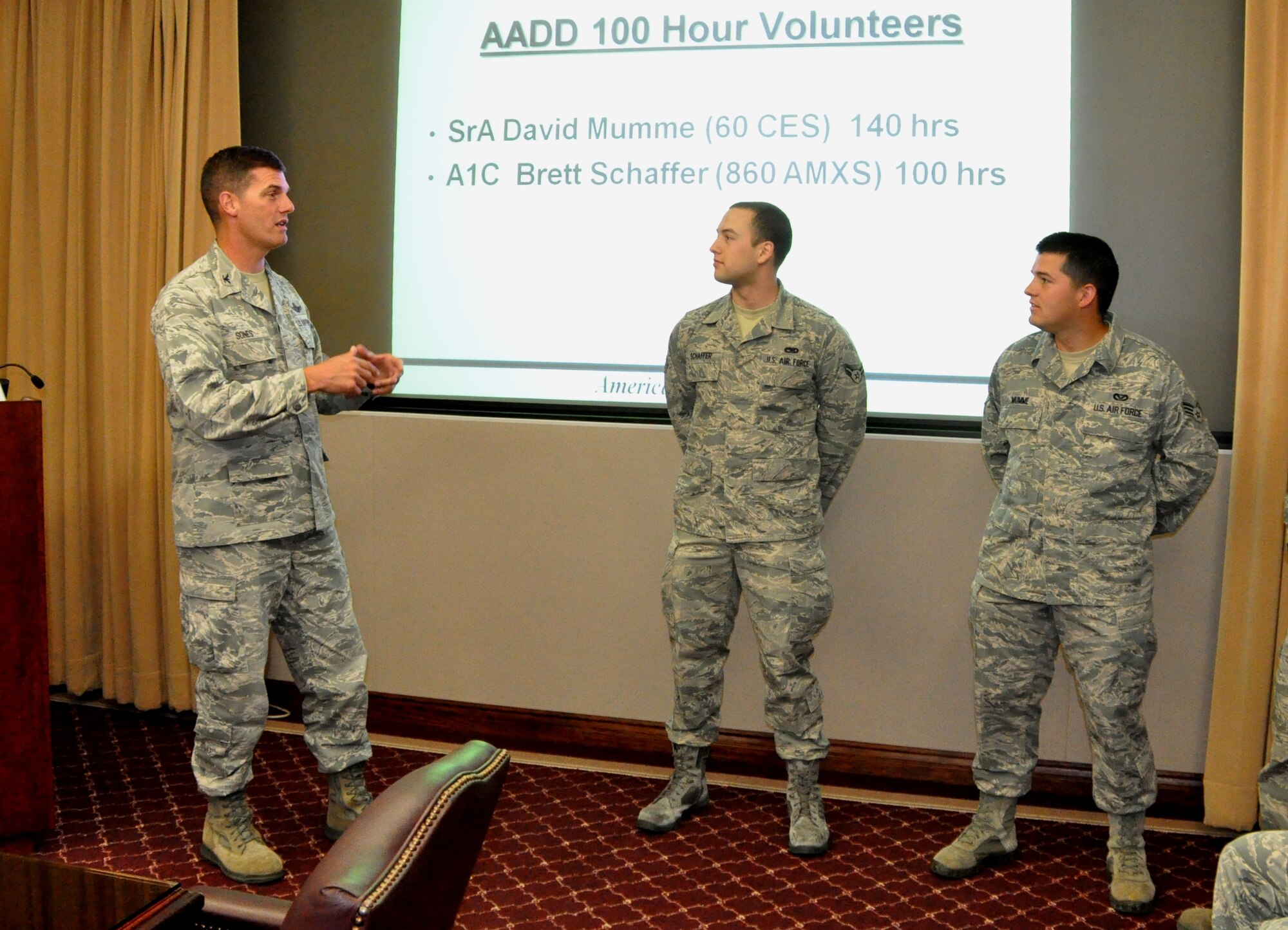 Col. Dwight Sones, 60th Air Mobility Wing commander (left), recognizes and coins two Airmen Against Drunk Driving volunteers in front of many members of the wing leadership during a briefing here Wednesday. Airman 1st Class Brett Schaffer, 860th Aircraft Maintenance Squadron (center), and Senior Airman David Mumme, 60th Civil Engineer Squadron, were two of 10 recently recognized by the commander for volunteering more than 100 hours toward the program. (U.S. Air Force photo/Senior Airman Bryan Swink)