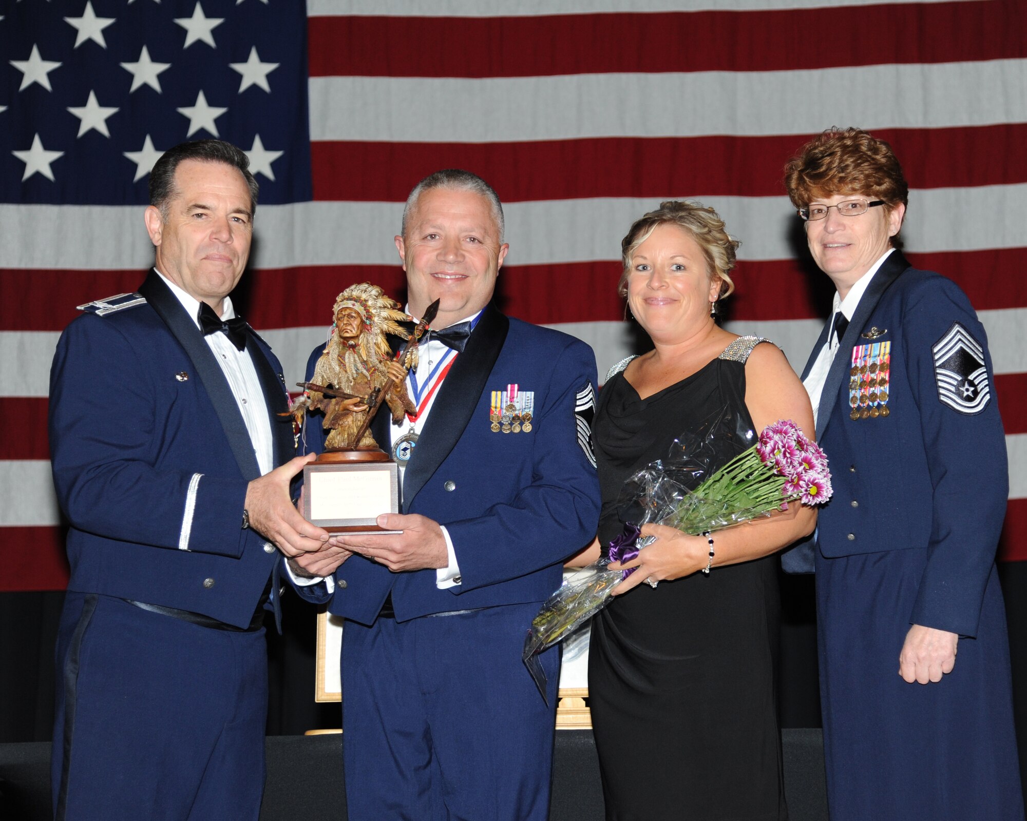 Col. Mark S. Larson, commander of the 931st Air Refueling Group, presents a Chief's Bust to Chief Master Sgt. Paul McGinnis during the McConnell Air Force Base Chief Recognition Ceremony, April 24, 2013.  Pictured with McGinnis are his wife as well as Chief Master Sgt. Kathleen E. Lowman, 931st Air Refueling Group Superintendent.  McGinnis was promoted to the rank of chief master sergeant in March 2013 and serves as the 931st Maintenance Group Superintendent in the Deputy Commander for Maintenance staff. (U.S. Air Force photo by Senior Airman Katrina Brisbin) 