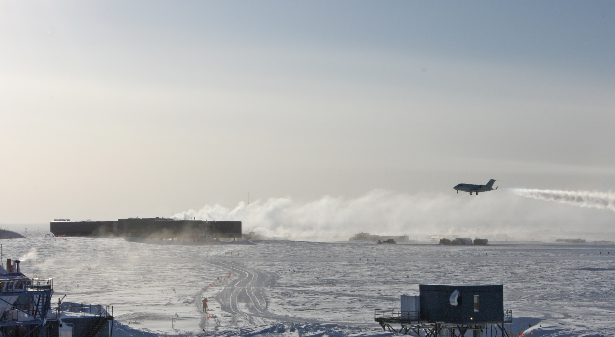 Snow blows in the distance at McMurdo Station, Antarctica as a 1st Aviation Standards Flight Bombardier Challenger flies overhead.  The Oklahoma crews are the only team in the world qualified to inspect McMurdo Station. (Courtesy Photo)   