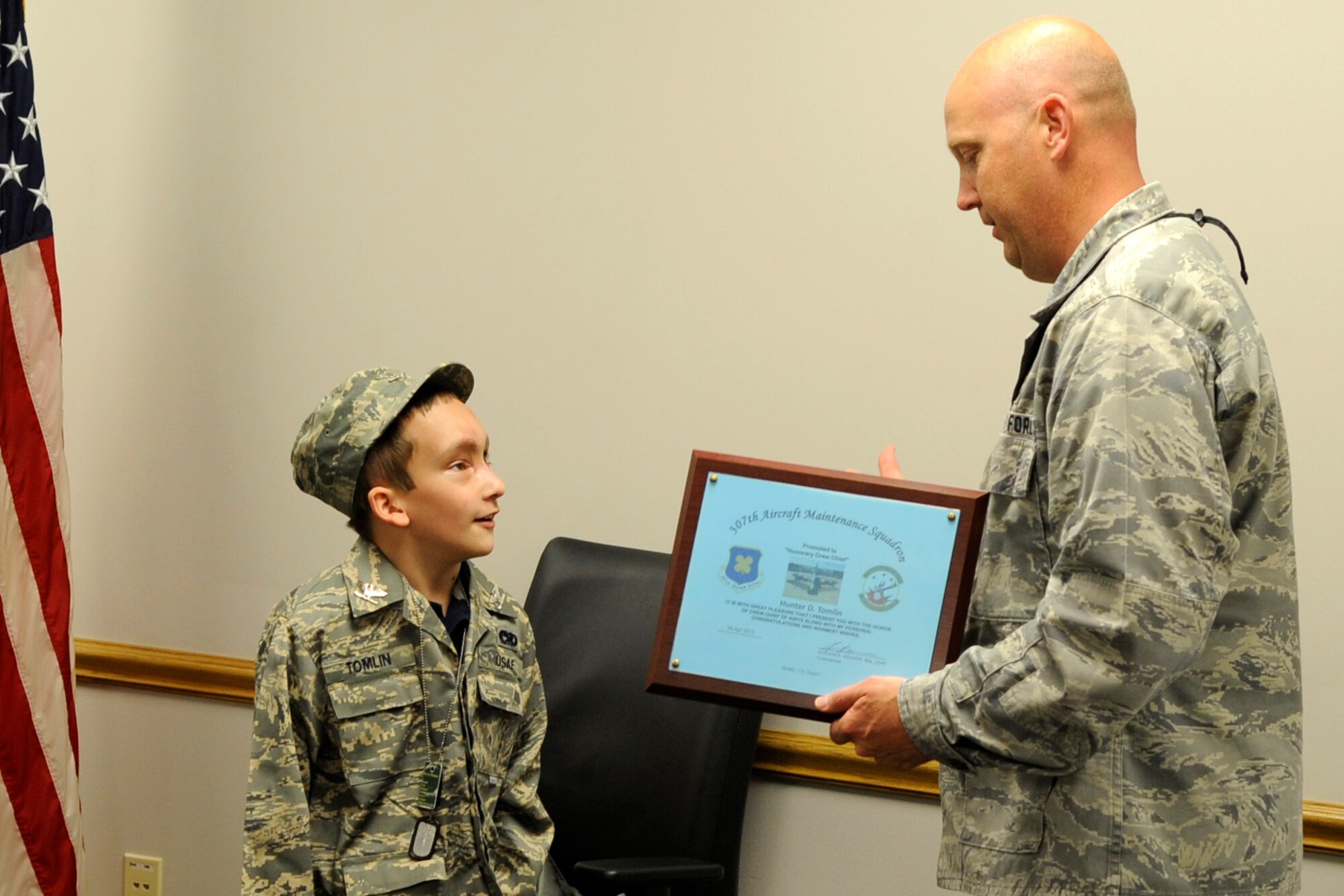 U.S. Air Force Maj. Karwin Weaver, who is the commander of the 307th Aircraft Maintenance Squadron, presents an Honorary Crew Chief certificate to 8-year-old Honorary Colonel Hunter Tomlin during ceremonies in Hangar 1 at Barksdale Air Force Base, La., April 24, 2013. Hunter, who has Neurofibromatosis Type 1, also known as von Recklinghausen disease, is recovering from surgery performed to remove a tumor from his face that hindered his ability to breathe through his nose. Members of the 307th AMXS and 2nd Aircraft Maintenance Squadron made Hunter’s dream come true by presenting him with an Air Force uniform, a tour of a B-52 Stratofortress and mementos of his visit to Barksdale. Weaver’s presentation to Hunter may make him the youngest, if not only, honorary colonel, honorary crew chief in the United States Air Force. (U.S. Air Force photo by Master Sgt. Jeff Walston)