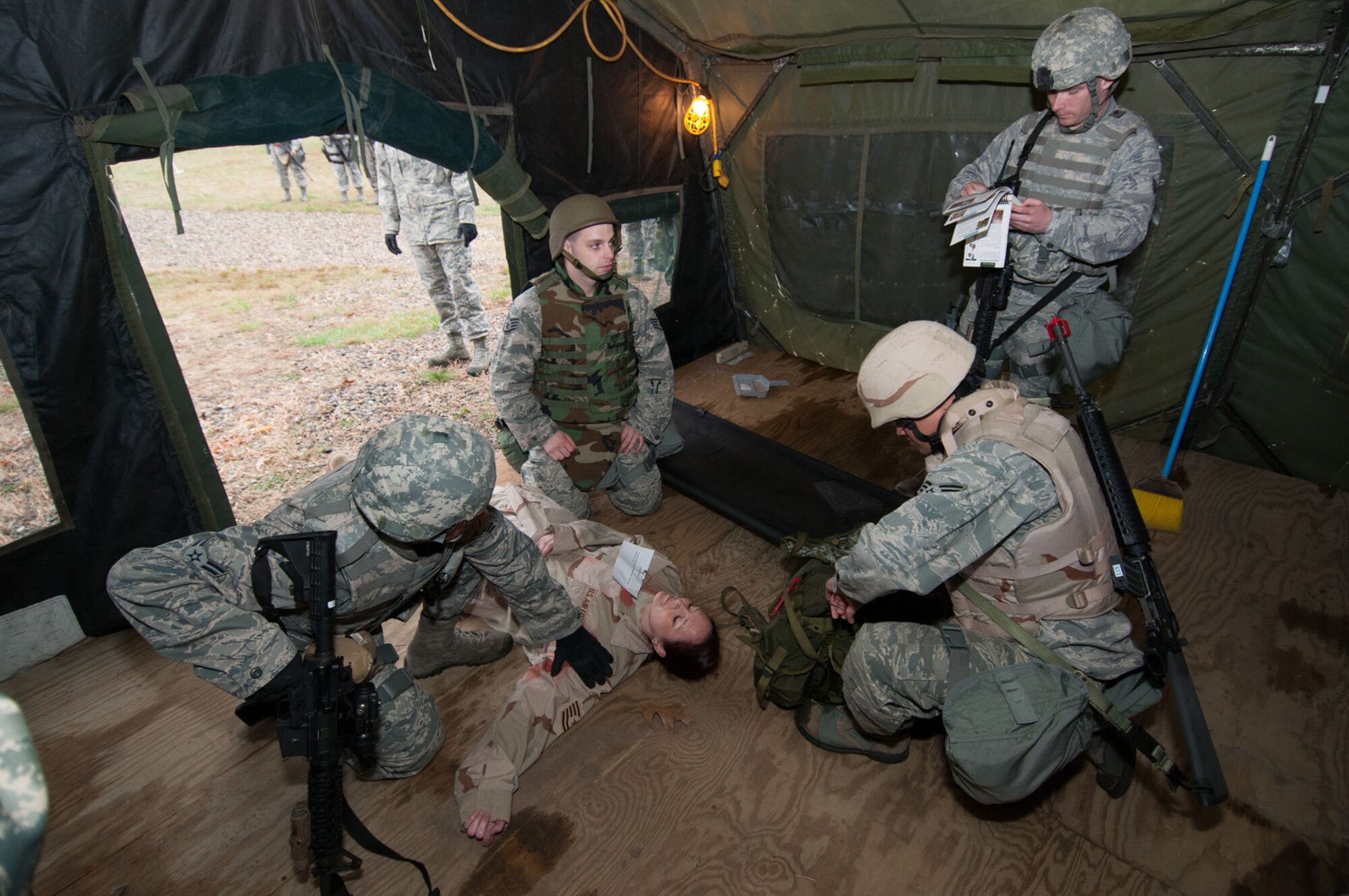 HANSCOM AIR FORCE BASE, Mass. – (clockwise from center) Staff Sgt. Michael Trala, Senior Airman Brent Seebeck, Senior Airmen Eliborio Castillo and Airman 1st Class Robert Stevens, perform simulated buddy aid to Tech. Sgt. Marissa Cross during the base readiness exercise at Camp Patriot April 23. The combat scenarios practiced during BREs are designed to help prepare personnel for deployed environments. (U.S. Air Force photo by Rick Berry)