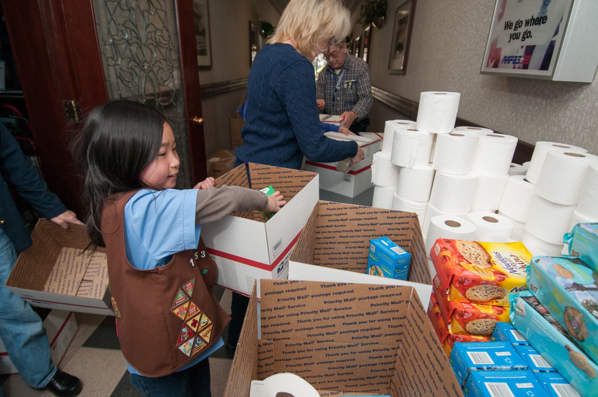 HANSCOM AIR FORCE BASE, Mass. – Sophia Gu, Girl Scout Troop 12953, places Girl Scouts cookies in packages during the Company Grade Officers Council Troop Care Drive at the Minuteman Thrift Shop April 17. The CGOC, along with many volunteers, assembled boxes to send items to deployed troops from Hanscom and neighboring units in the New England area. (U.S. Air Force photo by Rick Berry)