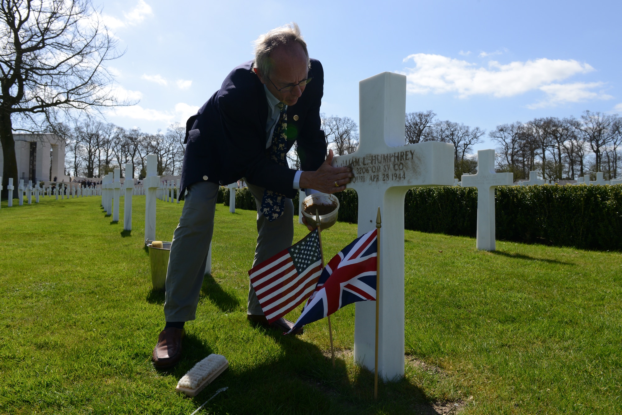 MADINGLEY, United Kingdom – Arthur Brooks, Cambridge American Cemetery cemetery associate, rubs sand from Normandy into the headstones of William Humphrey, who was killed during Exercise Tiger April 27, 1944. Members of the 423rd Air Base Group and its mission partners commemorated the 69th anniversary of the Exercise Tiger tragedy during a ceremony at Cambridge American Cemetery, in Madingley, United Kingdom, April 23. In all 749 American Soldiers and Sailors during one of several assault rehearsals in Exercise Tiger conducted at Slapton Sands on the Devon coast of England in preparation for the launch of Operation Overlord. (U.S. Air Force photo by Tech. Sgt. Chrissy Best)