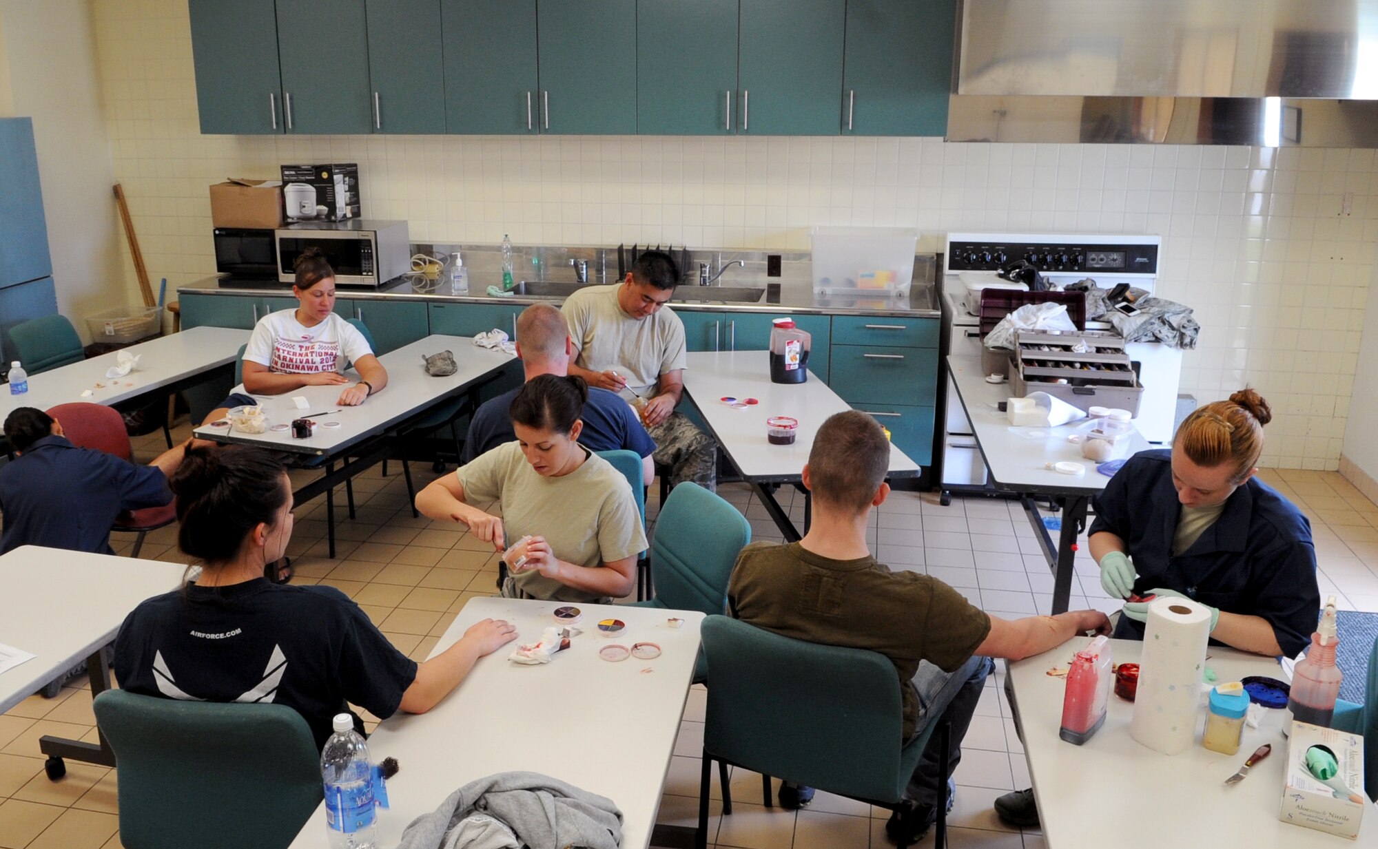 Participants in the emergency management exercise prepare with simulated injuries using stage make-up on Kadena Air Base, Japan, April 24, 2013. The injuries to the individuals sustained would have been the result of a tour bus crashing into a jet fuel tank during the training exercise. (U.S. Air Force photo by Airman 1st Class Keith A. James/Released)