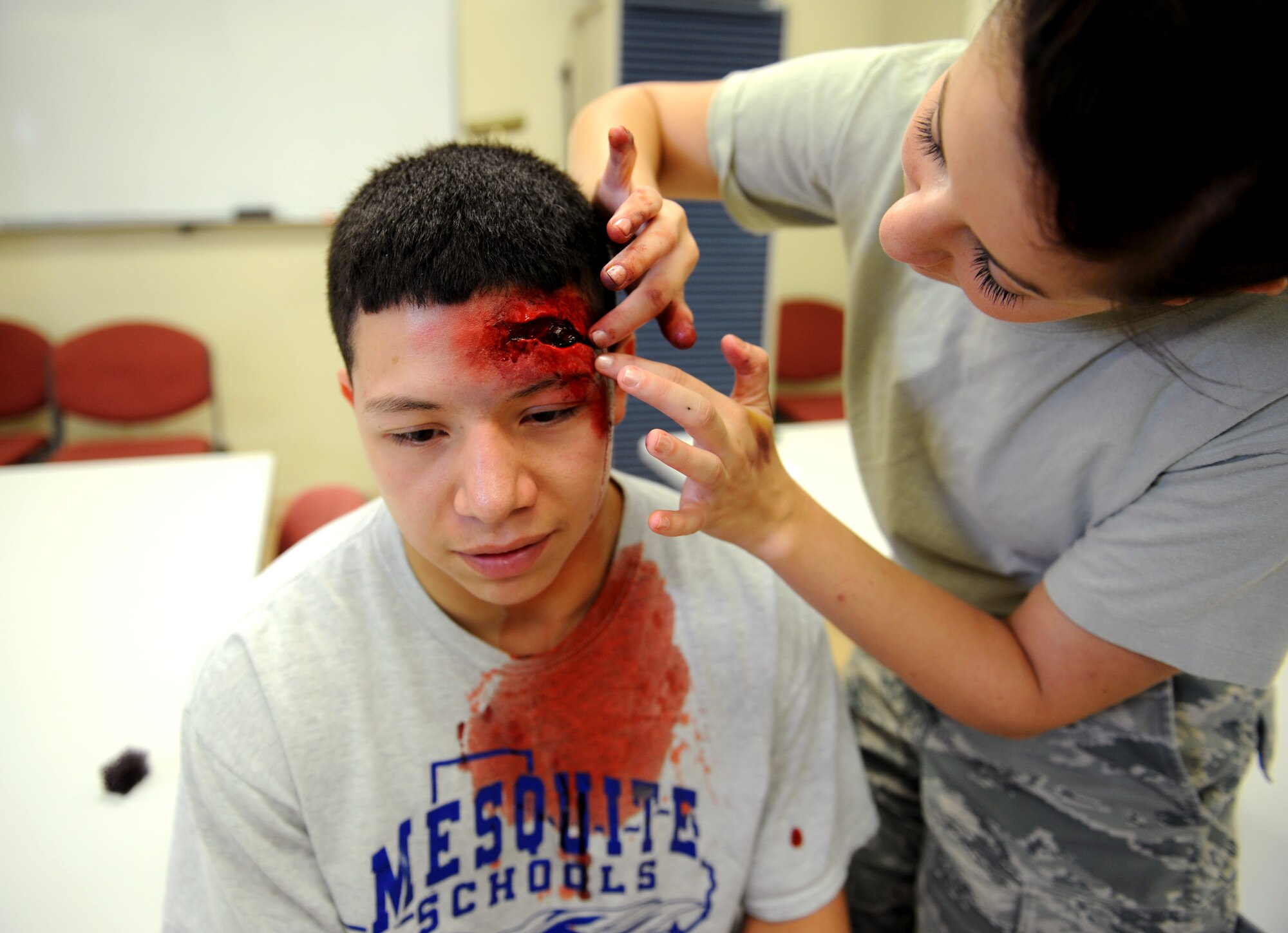U.S.  Air Force Senior Airman Kendra Wakefield,  18th Aero Medical Squadron aerospace and operational physiologist, applies stage make-up upon the forehead of Airman 1st Class Gerardo Romo ,18th Logistics Readiness Squadron central storage apprentice, on Kadena Air Base, Japan, April 24, 2013. Wakefield used the make-up to help simulate a severe head wound upon Romo?s  head for the emergency management exercise happening later that day. (U.S. Air Force photo by Airman 1st Class Keith A. James/Released)