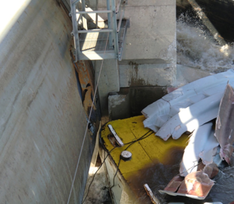 This photo shows damage to a concrete pier and the Tainter gate. Photo left, a 15-foot hole in the upstream portion of the Tainter gate; photo top, concrete damage to the upstream pier; photo right, barge cargo covers that were damaged after alliding with Marseilles Dam. 