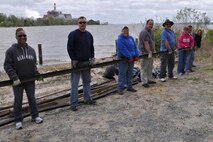 Volunteers carry a heavy piece of metal off the Potomac River beach April 22 during Marine Corps Systems Command's third annual Earth Day and Shoreline Cleanup event. MCSC's Safety Office orchestrated the event held at Hospital Point, Quantico, Va