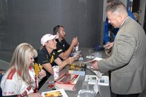 PETERSON AIR FORCE BASE, Colo. – Vaughn Fox, J64, shows off pictures of the hot rod he’s building in his garage to National Hot Rod Association racers Lori Johns and Karen Stoffer during an autograph signing session at North American Aerospace Defense Command and U.S. Northern Command headquarters July 22. Five of the NHRA racers came to meet fans and sign autographs before their race at Bandimere Speedway in Denver. 

(U.S. Air Force photo by Staff Sgt. Thomas J. Doscher) 

