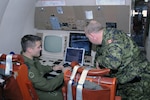 PETERSON AIR FORCE BASE, Colo. - Canadian Master Cpl. John Bowden, 407 Long Range Patrol Squadron Airborne Electronic Sensor Operator, shows Canadian Maj. Brian Martin, North American Aerospace Defense Command Public Affairs, the Electro-Optical Infrared Sensor station on board a CP-140 Aurora patrol aircraft on the Peterson AFB flight line Jan. 18. The "Demons" of 407 Squadron flew to Peterson AFB as part of pilot upgrade training and took the opportunity to visit Cheyenne Mountain Air Force Station and learn more about how their crew impacts the NORAD maritime warning mission. The CP-140 is a maritime patrol craft, and the 407 Squadron is responsible for patrolling for ships and submarines in the northern Pacific Ocean. 

(U.S. Air Force photo by Staff Sgt. Thomas J. Doscher) 

