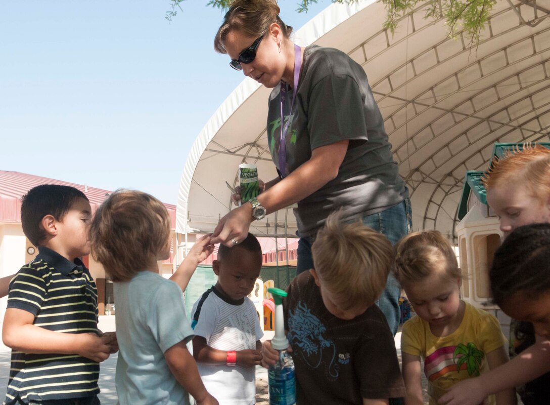 Jeanine Myllaly, a program assistant for the "Galaxy" class at the Child Development Center aboard Marine Corps Air Station Yuma, helps her pre-school class plant flower and vegetable seeds at the CDC, April 25. Various units and departments on MCAS Yuma participated in Earth Day activities to take part in raising awareness about the environment, as well as take local action to support and highlight our global reach, which is the Marine Corps Earth Day theme for 2013.