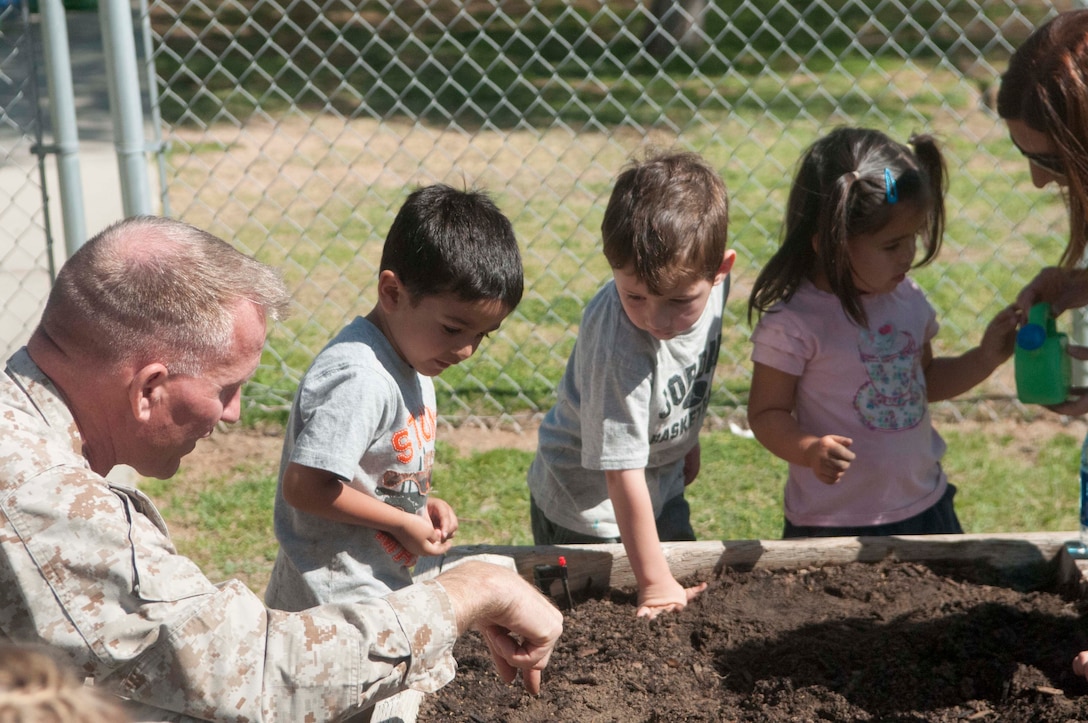 The commanding officer of Marine Corps Air Station Yuma, Col. Robert Kuckuk, helps a group of children from the Child Development Center plant flower and vegetable seeds in the soil, as part of an MCAS Yuma Earth Day activity on April 25. The event was a collaboration between MCAS Yuma's Environmental Department and the CDC as a part of the week-long Earth Day celebration for Marines and their families.  The goal of the week was to raise awareness of sound environmental stewardship and to reaffirm MCAS Yuma's commitment to environmental compliance and protection.