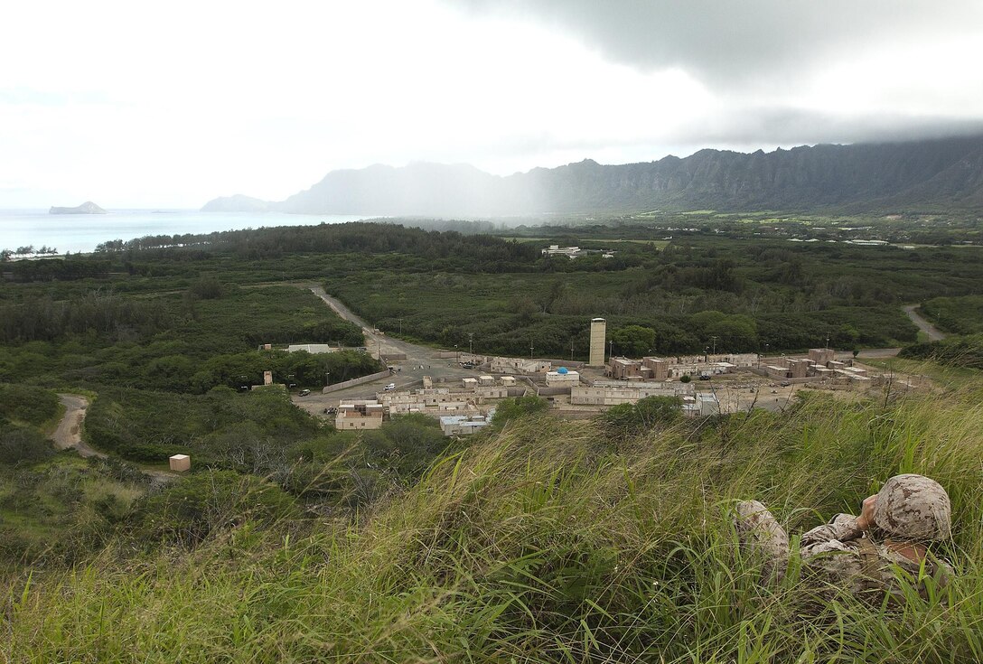 A Marine with 3rd Battalion, 3rd Marine Regiment observes a mock Afghan village and role-players through his binoculars from an observation point outside the village during the Combat Hunter course at Marine Corps Training Area Bellows, Hawaii, April 17, 2013. The goal of the training exercise was to identify things out of place and report them to fellow Marines. (U.S. Marine Corps photo by Lance Cpl. Matthew Bragg)