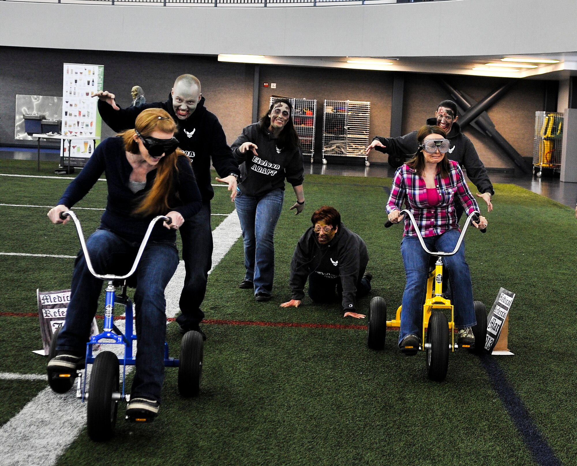 Jessica Mann, wife of Senior Master Sgt. Jon Mann, 354th Operations Support Squadron superintendent, and Christy Hedrick, wife of Master Sgt. Ricky Hedrick 354th Maintenance Squadron conventional maintenance NCO in charge, race from zombies with beer goggles on during an alcohol awareness event April 18, 2013, Eielson Air Force Base, Alaska. Eielson’s Alcohol and Drug Abuse Prevention and Treatment team hosted a zombie-themed event to raise awareness on the effects of alcohol on the human body. (U.S. Air Force photo by Senior Airman Racheal E. Watson/Released)