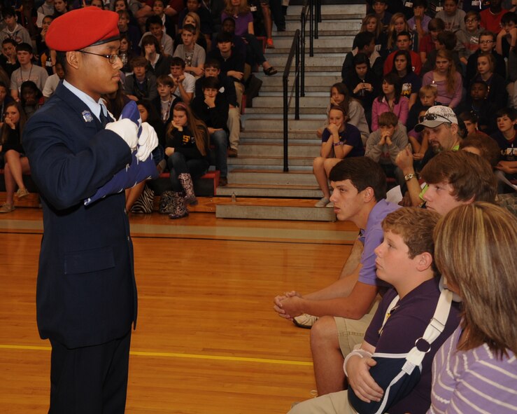 A member of the Parkway High School Air Force Junior Reserve Officer Training Corps presents a flag to the son of Tech. Sgt. Larry Bunn, 307th Maintenance Squadron, who passed away while deployed to Southwest Asia during the Purple Up Day Mayoral Proclamation event at Elm Grove Middle School, Bossier City, La., April 26, 2013. During the ceremony, Mayor Lorenz Walker dedicated April 26 as National Purple Up Day. The event was held to show support for military students and families. (U.S. Air Force photo/Senior Airman Sean Martin)