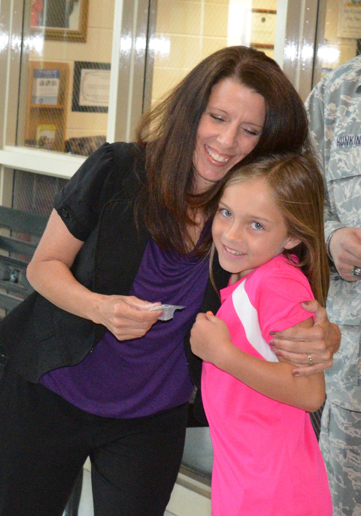 Reneee Daughtry, Robins School Liaison Officer, hugs Peyton McCaskill, as she receives her dog tag. (U.S. Air Force photo by Ed Aspera)