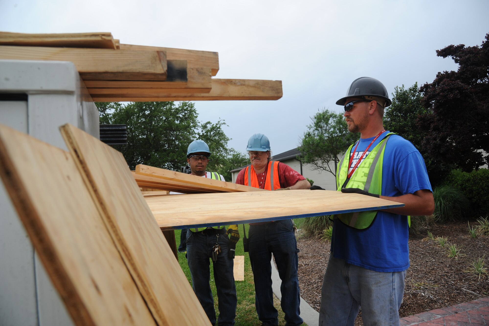 Kenneth King, John Akins and Jeremy Railey, Computer Sciences Corporation contractors, unload wood from the back of a truck to board up windows and doors on the 2nd Air Force building during a hurricane exercise April 24, 2013, at Keesler Air Force Base, Miss.  Throughout the exercise, “Hurricane Hana” brought severe thunderstorms, F2 tornado strength winds, rain and hail damage to several base facilities.  The purpose of the exercise was to prepare Keesler for the upcoming hurricane season.  (U.S. Air Force photo by Kemberly Groue)