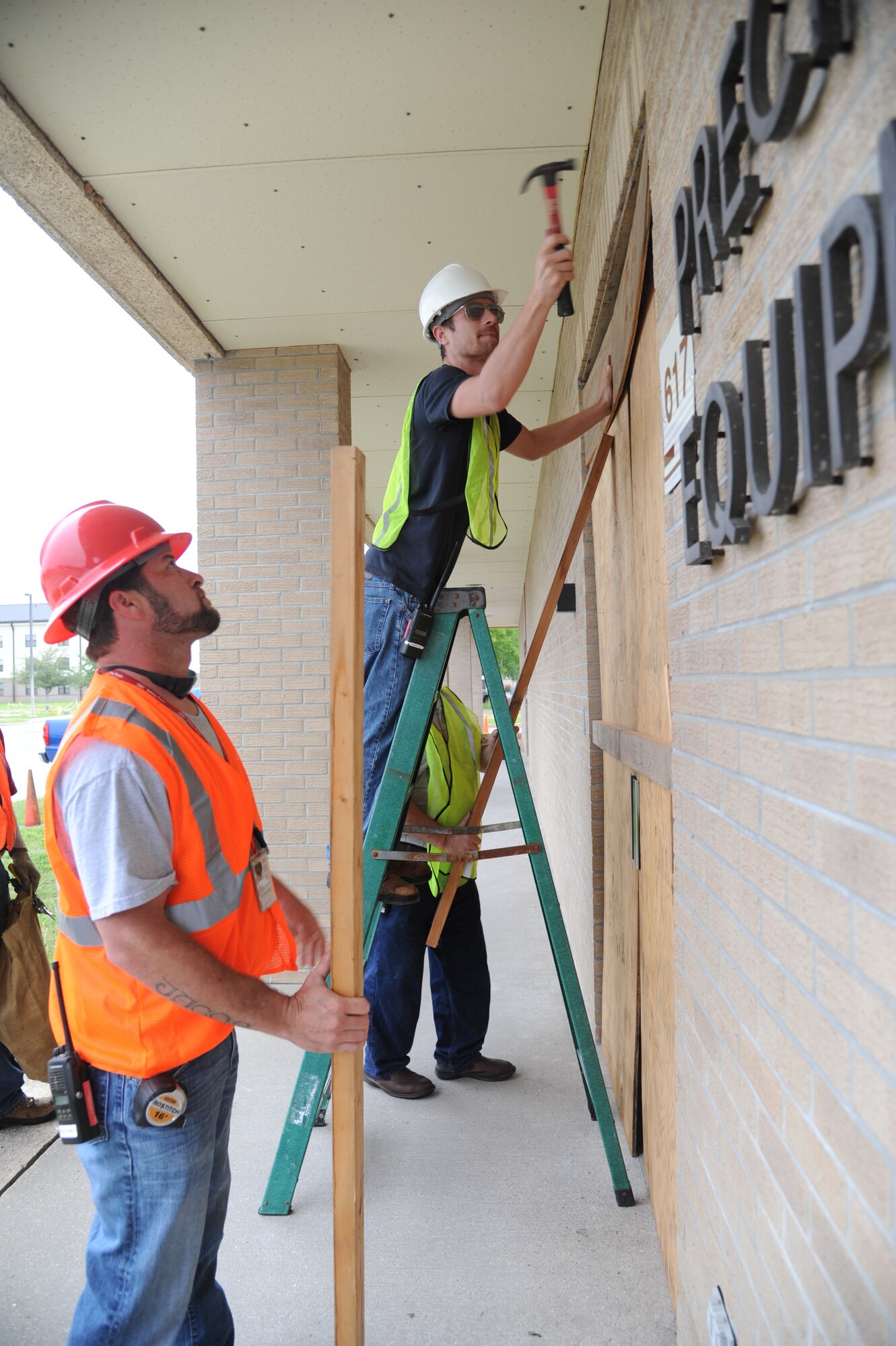 Dennis Fink and Thomas Frisbie, Computer Sciences Corporation contractors, secure boards in front of doors and windows at the Precision Measurement Equipment Laboratory during a hurricane exercise April 24, 2013, at Keesler Air Force Base, Miss.  Throughout the exercise, “Hurricane Hana” brought severe thunderstorms, F2 tornado strength winds, rain and hail damage to several base facilities.  The purpose of the exercise was to prepare Keesler for the upcoming hurricane season.  (U.S. Air Force photo by Kemberly Groue)