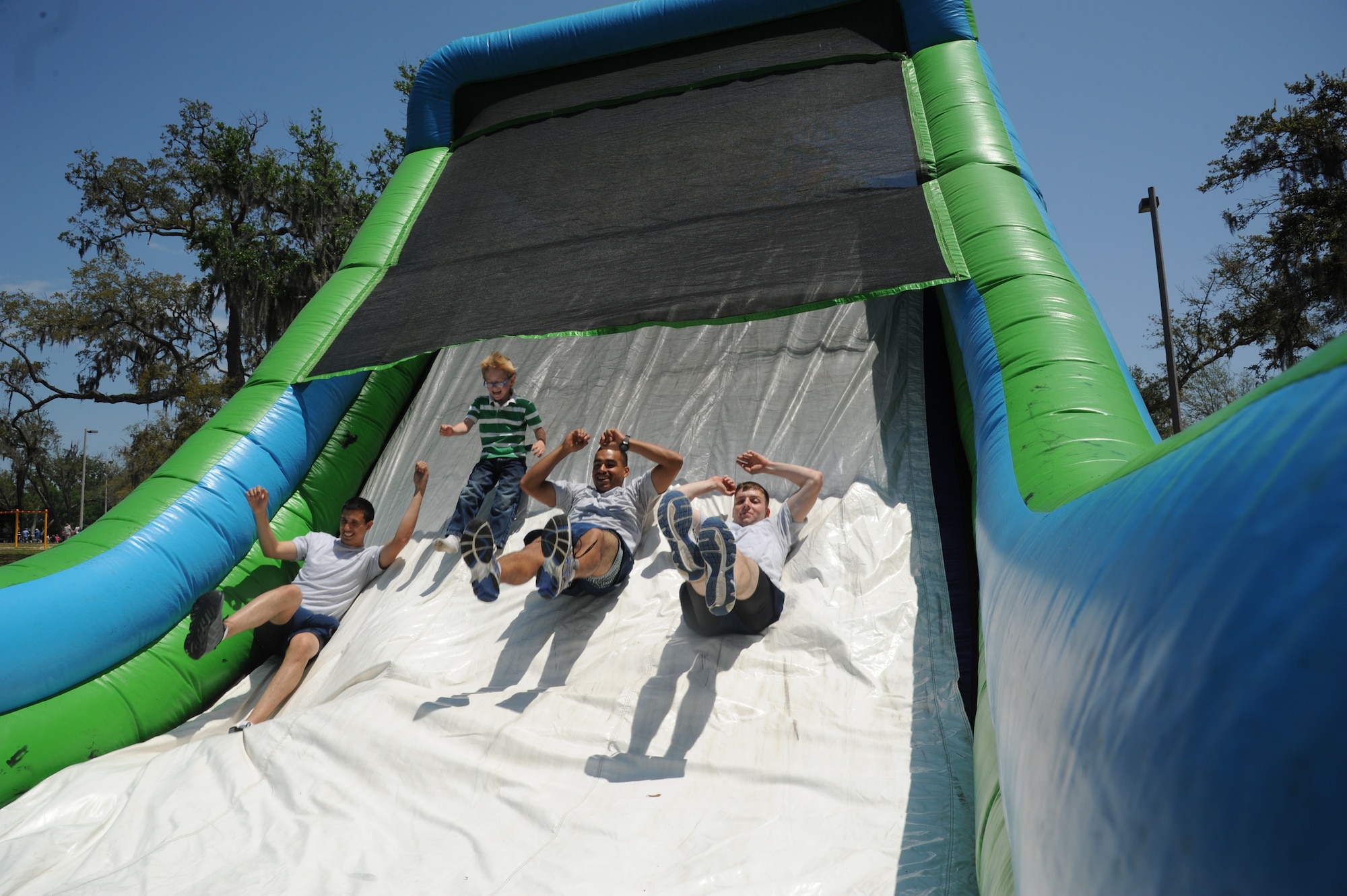 Airman Darvin Williams, 338th Training Squadron, Joel Ahern, 7, Airman Roberto Valdez, 338th TRS, and Airman 1st Class Kyle Porter, play on an inflatable slide during the Commander-in-Chief’s Installation Excellence award base picnic at the Marina park April 25, 2013, Keesler Air Force Base, Miss.  Joel’s parents are Christy and Tech. Sgt. Jimmy Ahern, 335th TRS.  The event consisted of free food and beverages, music, games and an awards presentation.  (U.S. Air Force photo by Kemberly Groue)