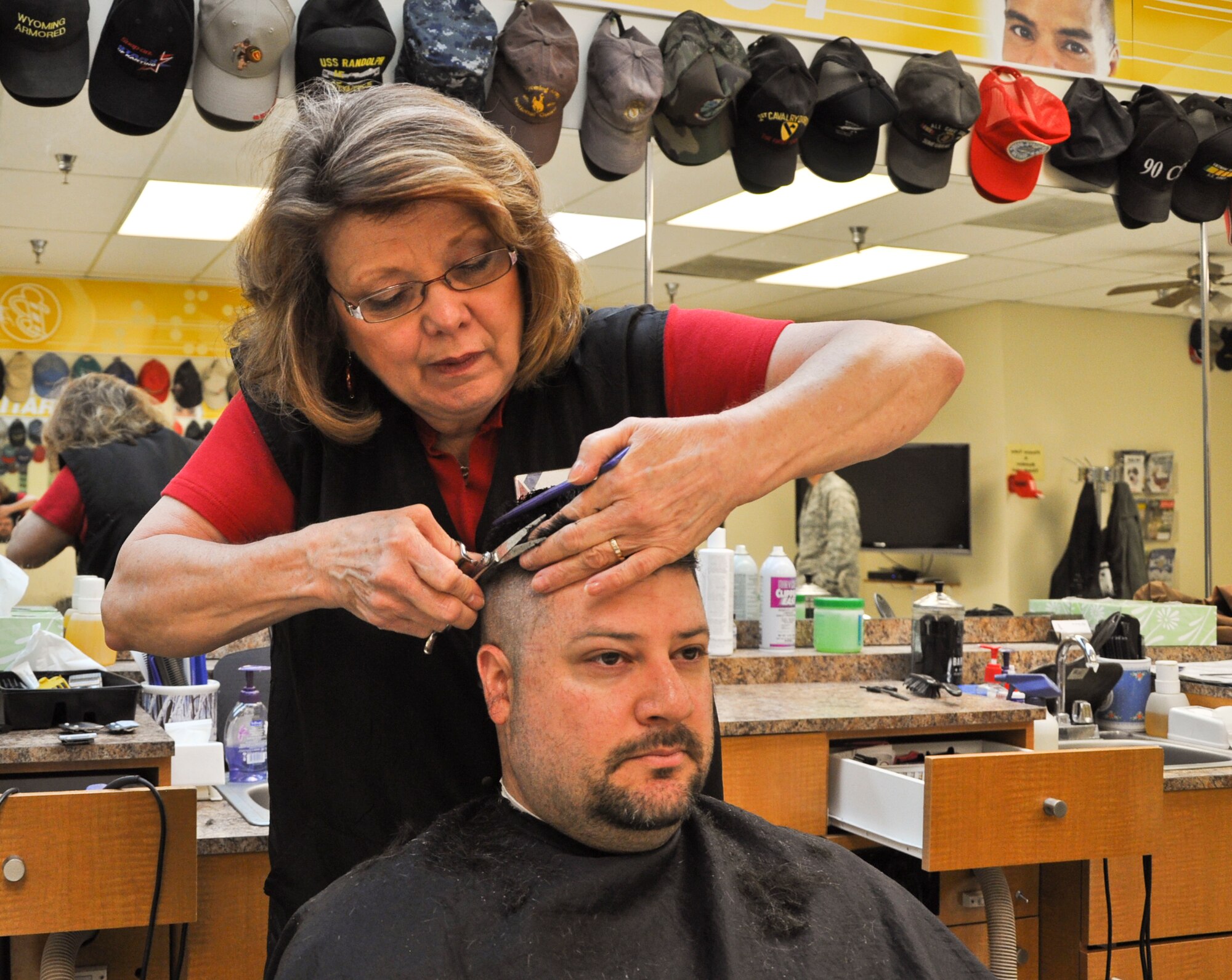 Rita Gentry, F. E. Warren Base Exchange Barber Shop manager, cuts Tech. Sgt. Ed Ginsberg’s hair. Ginsberg is a member of the 137th Space Warning Squadron with the Air National Guard. This is one of the up to 40 haircuts Gentry will cut in one day and one of the last ones she will do at Warren. She retires April 27. (U.S. Air Force photo by 2nd Lt. Christen Downing)