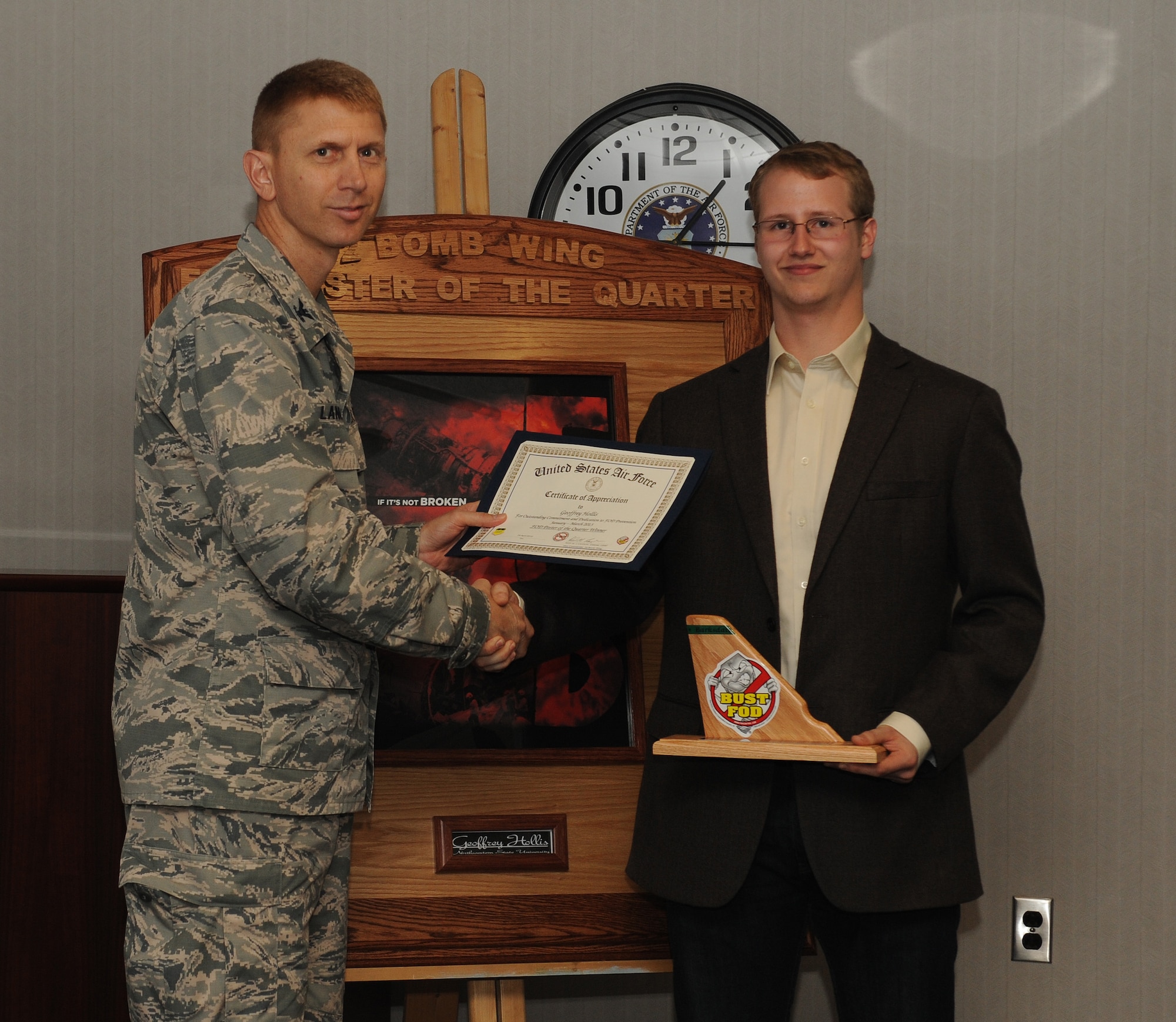 Col. Reid Langdon, 2nd Bomb Wing vice commander, presents a certificate of recognition and personalized tail flash plaque to Geoffrey Hollis, a student from Northwestern State University of Louisiana, Natchitoches, La.,  for his winning foreign object debris or ?FOD? poster submission at Barksdale Air Force Base, La., April 24, 2013. The FOD poster contest is used to promote awareness and help reduce the number of FOD incidents that caused more than $3 million of damage the past 5 years. (U.S. Air Force photo/Airman 1st Class Benjamin Gonsier)