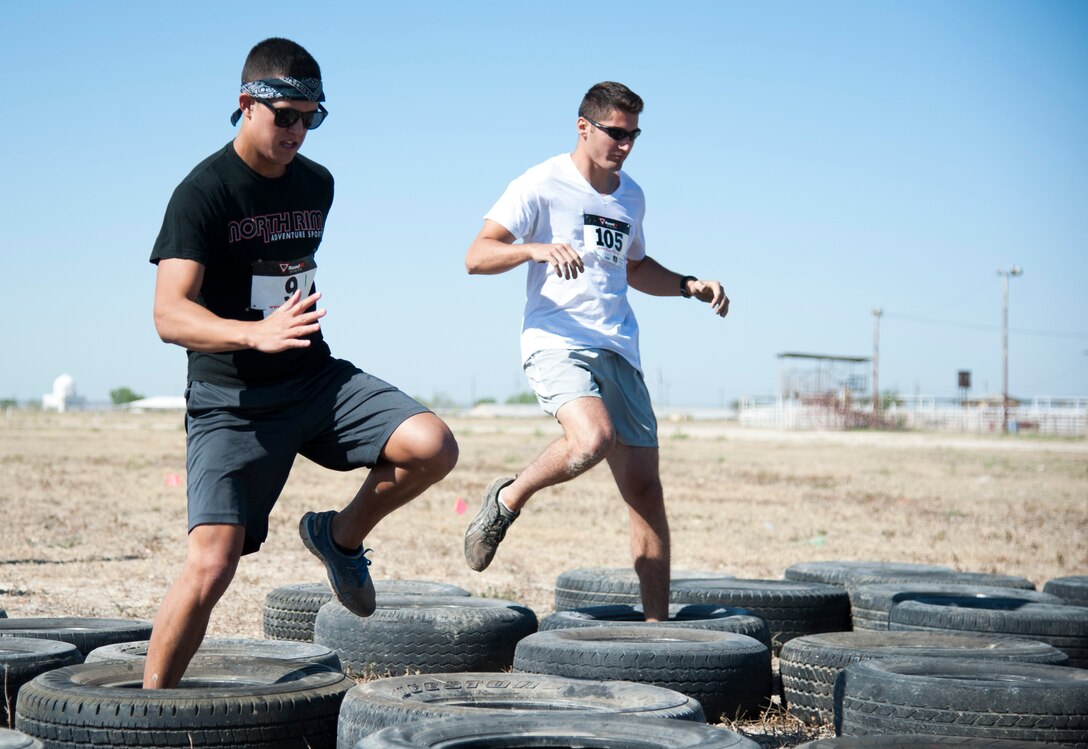 Second Lt. Tate Montgomery, left, and 2nd Lt. Marc Anderson, both 47th Student Squadron, jump through a tire obstacle in Del Rio’s first Battle on the Border Mud Crawl at the Val Verde County Fairgrounds April 20, 2013. The Del Rio Chamber of Commerce and 85th Flying Training Squadron's Booster Club brought the event together for Laughlin and local community members to have a day of family fun. (U.S. Air Force photo/Airman 1st Class John D. Partlow)
