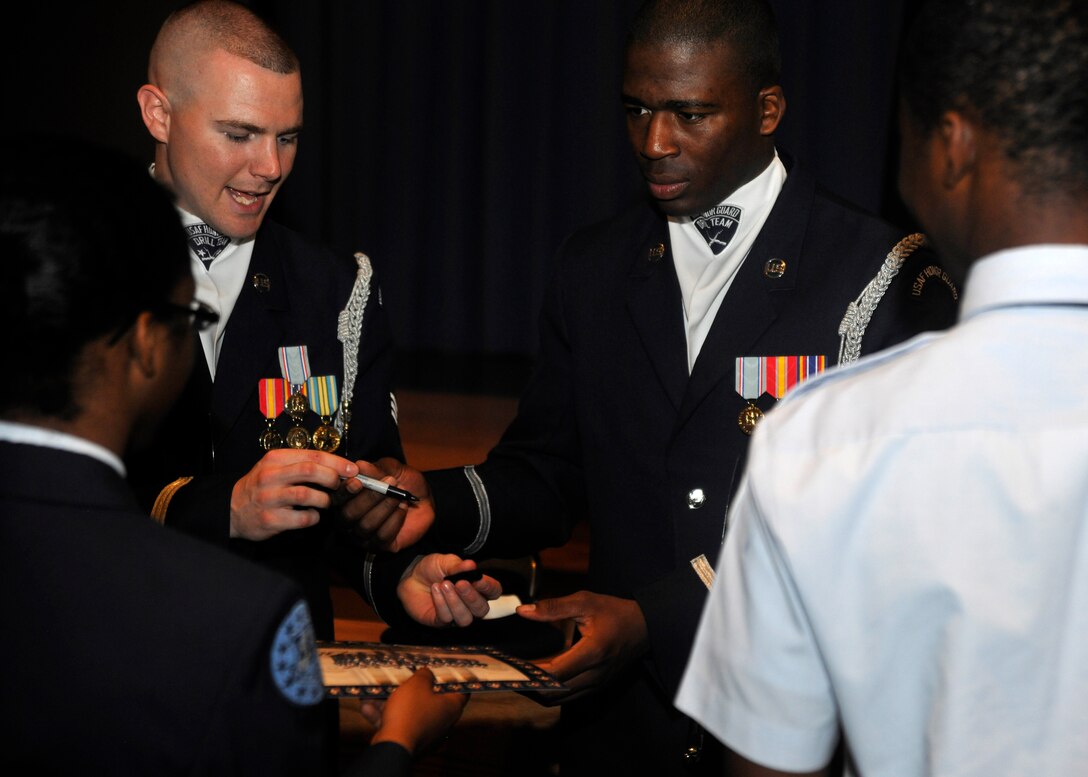 Staff Sgt. Andrew Winders, left, U.S. Air Force Honor Guard Drill Team member, and Senior Airman Jimmie Pryor, Honor Guard Drill Team member, sign autographs for students after performing at Indian River High School in Virginia Beach, Va. April 19, 2013. The team performed in conjunction with a POW recognition ceremony given by the school’s AFJROTC unit. (U.S. Air Force photo/Senior Airman Lindsey A. Porter)