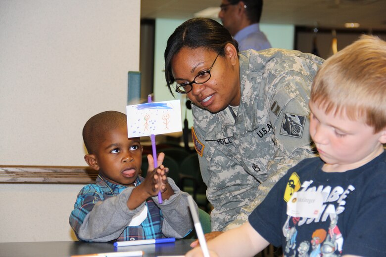 Staff Sgt. Leah Holly, an SWD administrative assistant, admires her 5-year-old sons art project displaying animation during Take Your Sons and Daughter to Work Day.