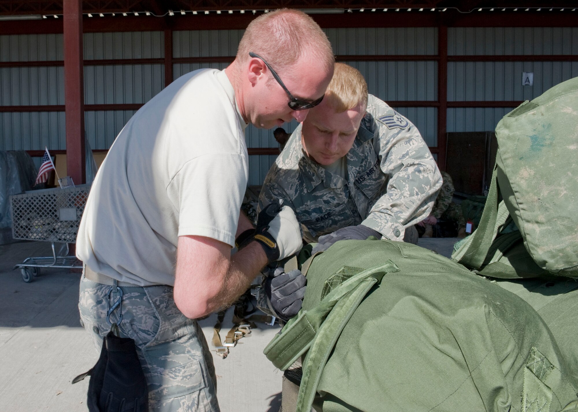 Senior Airman Matthew Hanning, 376th Expeditionary Logistics Readiness Squadron baggage yard specialist, and Staff Sgt. Duane Pace, 376 ELRS baggage yard assistant supervisor, tighten a baggage net April 27, 2013, at Transit Center at Manas, Kyrgyzstan. "Because the Transit Center is a passenger movement location, our primary mission is to control inbound and outbound bags," said Pace. "A Soldier, Sailor, Airman or Marine is a valuable tool, but without their gear and equipment, they are not as useful." (U.S. Air Force photo/Staff Sgt. Stephanie Rubi)
