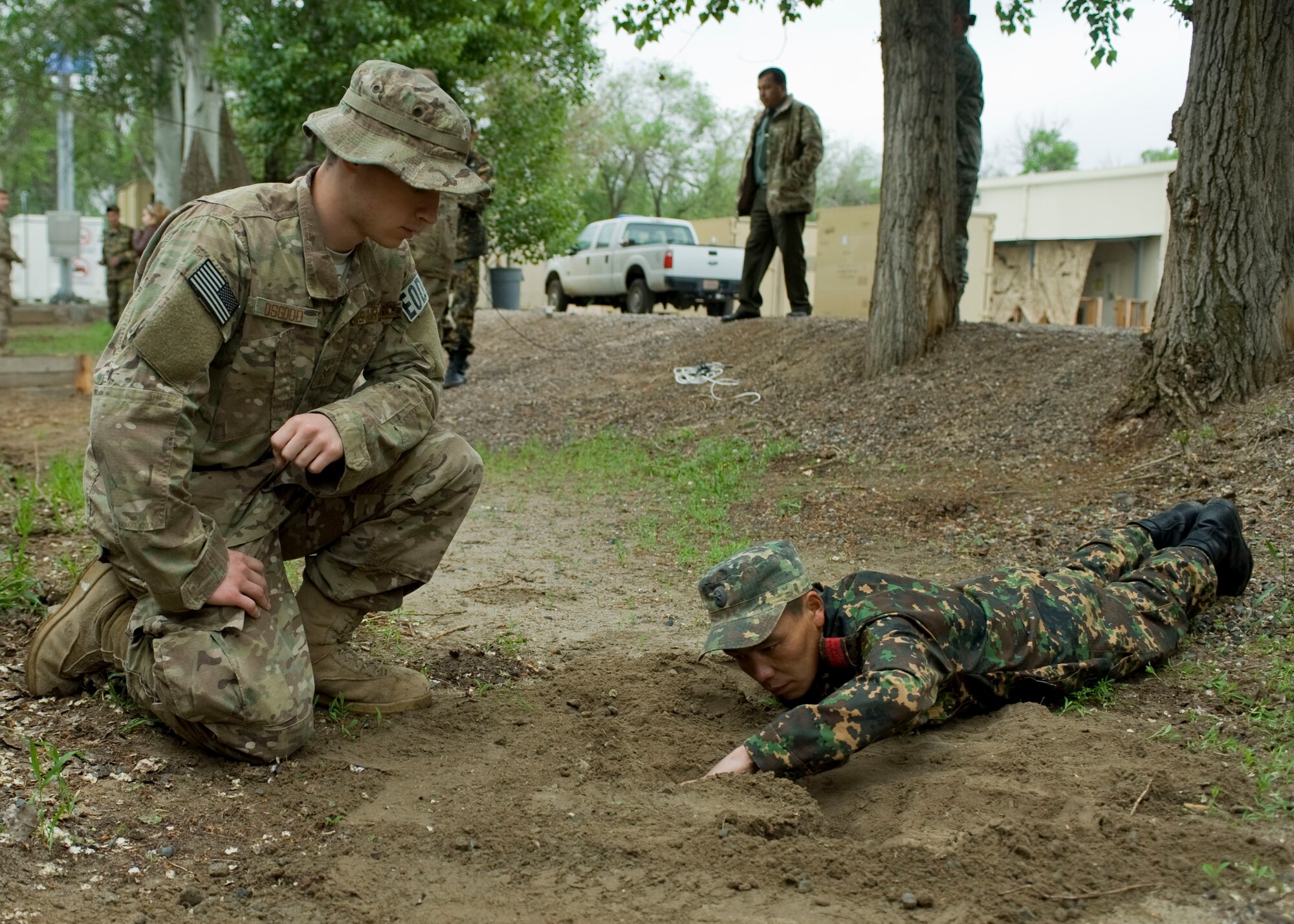 Senior Airman Kyle Osgood, 376th Expeditionary Civil Engineer Squadron explosive ordnance disposal team member, and Sgt. Ulanbek Jidebaev, Ministry of Defense explosive ordnance disposal team member, uncover a training landmine during an EOD military exchange April, 24, 2013, at Transit Center at Manas, Kyrgyzstan.  "I was able to assist in demonstrating our tools and equipment to our Kyrgyz counterparts," said Osgood. I've really enjoyed this experience; it's my first time working with a foreign military. The language barrier could have presented some difficulty but we are lucky to have such great interpreters." (U.S Air Force photo/Staff Sgt. Stephanie Rubi)