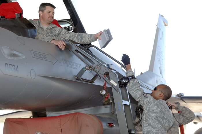 ELLINGTON FIELD, Texas - Tech. Sgt. Chris Hase takes a technical manual from Staff Sgt. Christopher Boyd during a weapons download and functional test of an F-16 fighter during an Amalgam Mute inspection March 15. As well as inspecting a unit's ability to employ and control aircraft, North American Aerospace Defense Command Inspector General personnel also inspect and grade the unit on their ability to maintain and reconstitute their aircraft following a mission. Hase and Boyd are aircraft armament systems specialists with the 138th Fighter Wing, Detachment 1. 

(U.S. Air Force photo by Tech. Sgt. Thomas J. Doscher) 

