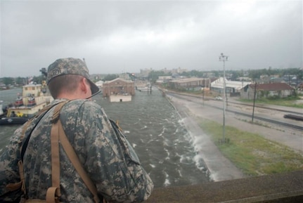 A Louisiana National Guardsman observes from the Claiborne Ave. bridge in New Orleans as water from the Industrial Canal overtops the levees and pours into the city Monday.