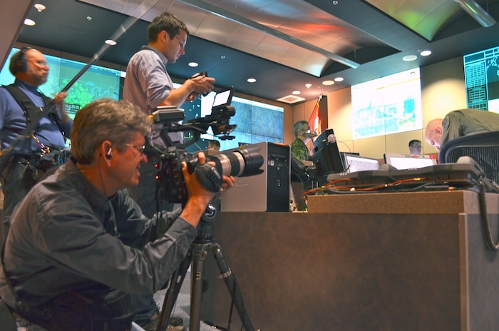 CHEYENNE MOUNTAIN AIR FORCE STATION, Colo. - Partisan Pictures’ cameraman Ben McCoy collects film footage of a multi-threat NORAD and USNORTHCOM exercise in the Alternate Command Center at Cheyenne Mountain Air Force Station. Immediately behind him are assistant producer Tristan Walker and sound specialist Thomas Wilson (far left). Royal Canadian Air Force Lieutenant-Colonel Joe Barry (center) and U.S. Air Force Colonel Chris Possehl (far right) are in the background. Partisan Pictures captured film footage at Cheyenne Mountain Air Force Station for a documentary project during the second week of April 2012. 

(Canadian Forces photo by Lt. Alain Blondin) 


