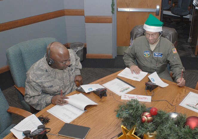 PETERSON AIR FORCE BASE, Colo. - NORAD Tracks Santa volunteers Col. Alvin Vann and Maj. Miguel Pagan answer phone calls from people across the globe looking for Santa. The green hat Pagan is wearing signifies that he speaks a second language and is available to translate should another volunteer receive a call in that language. (U.S. Air Force photo by Tech. Sgt. Thomas J. Doscher)