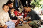 Master Sgt. Tina Williams, 163d Reconnaissance Wing budget analyst, puts a new pair of shoes on a young Guatemalan boy. Sergeant Williams accompanied the 163d Medical Group to ensure the team was able to purchase needed supplies at each site.