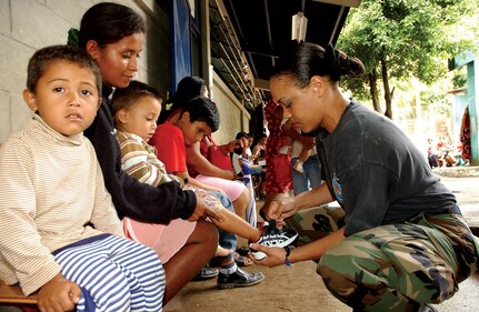 Master Sgt. Tina Williams, 163d Reconnaissance Wing budget analyst, puts a new pair of shoes on a young Guatemalan boy. Sergeant Williams accompanied the 163d Medical Group to ensure the team was able to purchase needed supplies at each site.